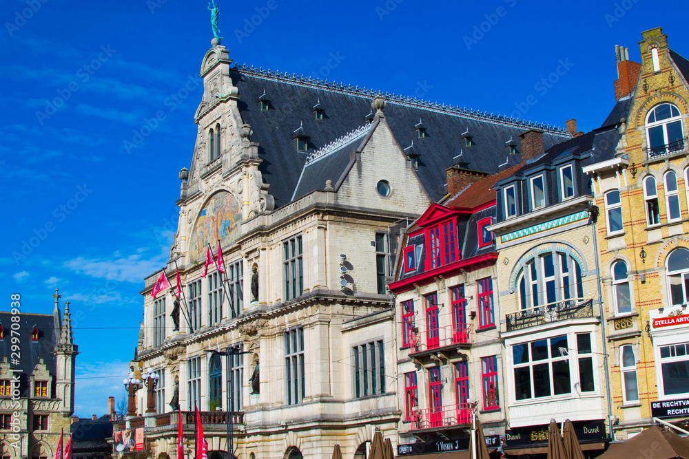 Naklejka premium Ghent, Belgium; 10/26/2019: Nederlands Toneel Gent (NTGent or NTG), a famous theatre in Sint-Baafsplein square, with traditional colorful belgian houses during a sunny day