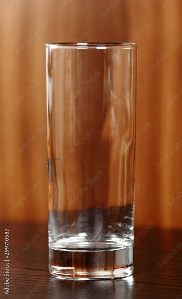 Empty highball glass at wooden brown background Empty highball glass at wooden brown background