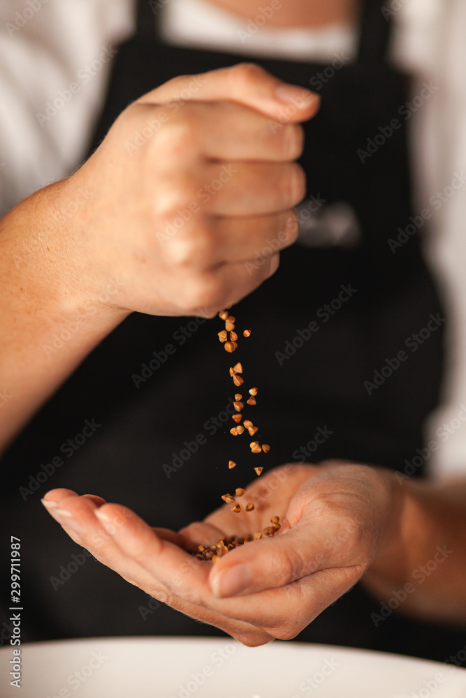 Buckwheat grains fall from one hand to another. Buckwheat grains fall from one hand to another.