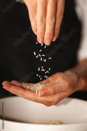 Rice grains fall from one hand to another.