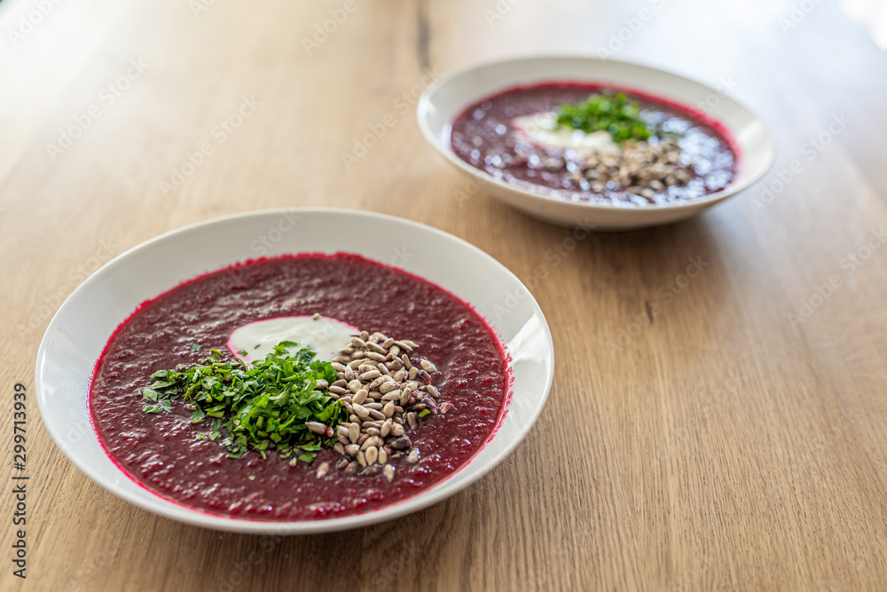 White plate of beetroot soup with parsley and sunflower seeds. Vegetarian dish, fresh soup. White plate of beetroot soup with parsley and sunflower seeds. Vegetarian dish, fresh soup.