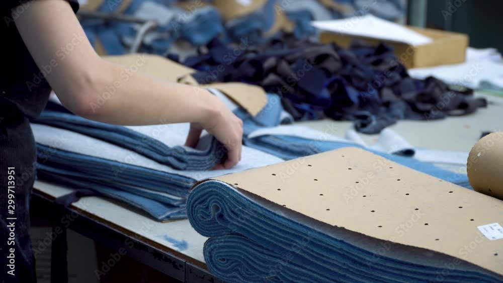 The worker of the sewing factory collects pieces of fabric cut by the automatic laser machine into sets. 4k footage.