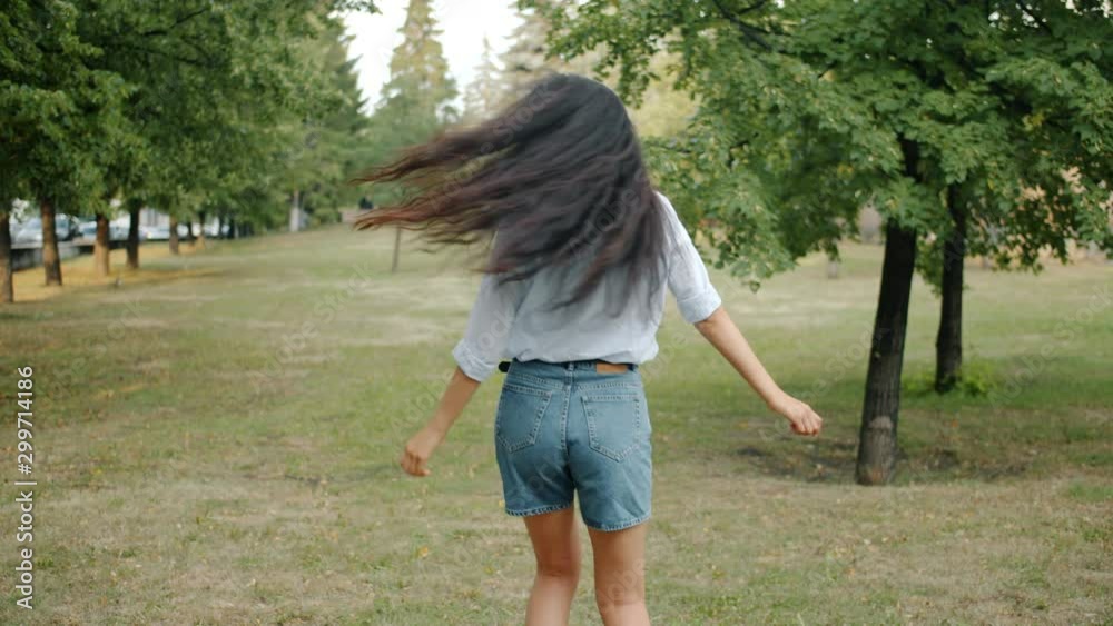 Slow motion of happy Asian girl in trendy clothing dancing in city park smiling enjoying leisure time and nature. People, lifestyle and happiness concept. Slow motion of happy Asian girl in trendy clothing dancing in city park smiling enjoying leisure time and nature. People, lifestyle and happiness concept.