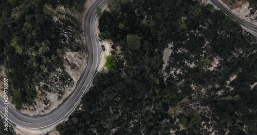Drone shot of a parked black car near a winding road in the mountains with a dark forest (Santa Anita Canyon, California, USA) photo