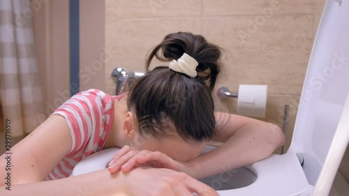Young sick woman is going toilet to vomit sitting on the floor at home, side view, flu symptom, side view. photo
