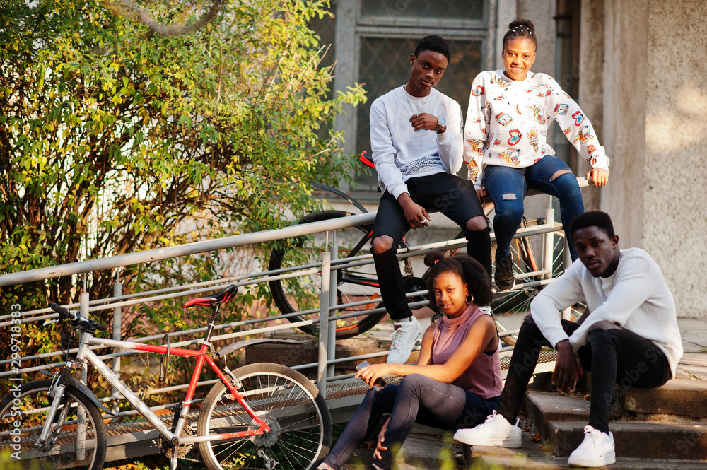 Obraz premium Four african friends walking the streets of an ancient city with bilkes.
