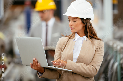 Businesswoman in warehouse. Young female architect with helmet in suit. Close up.