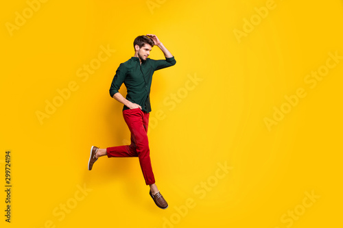 Turned ful llength body size photo of serious fashionable man with hand in red pants pocket running for sales towards barbershop for cheap service isolated vibrant color background