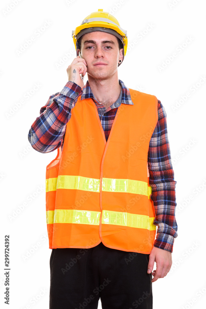 Portrait of young handsome man construction worker talking on the phone