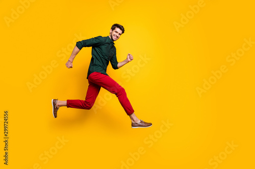 Full length body size side profile photo of cheerful positive nice handsome man in green shirt running to empty space smiling toothily isolated vibrant color background