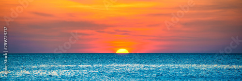 Panorama of nature landscape with beautiful dramatic orange sunset over blue wave sea