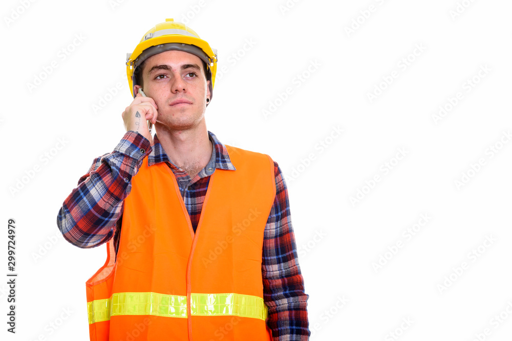 Young man construction worker thinking while talking on the phone Young man construction worker thinking while talking on the phone