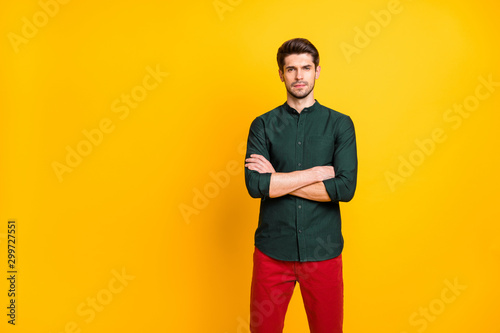 Photo of serious attractive confident man standing with arms crossed wearing red trousers watching his employees pass final test to get job isolated over yellow bright color background