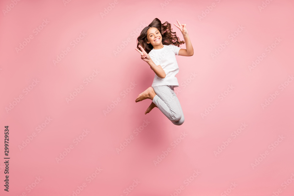 Full length body size photo of cheerful at leisure barefoot positive cute curly wavy preteen showing you double v-sign jumping up isolated pastel color background Full length body size photo of cheerful at leisure barefoot positive cute curly wavy preteen showing you double v-sign jumping up isolated pastel color background