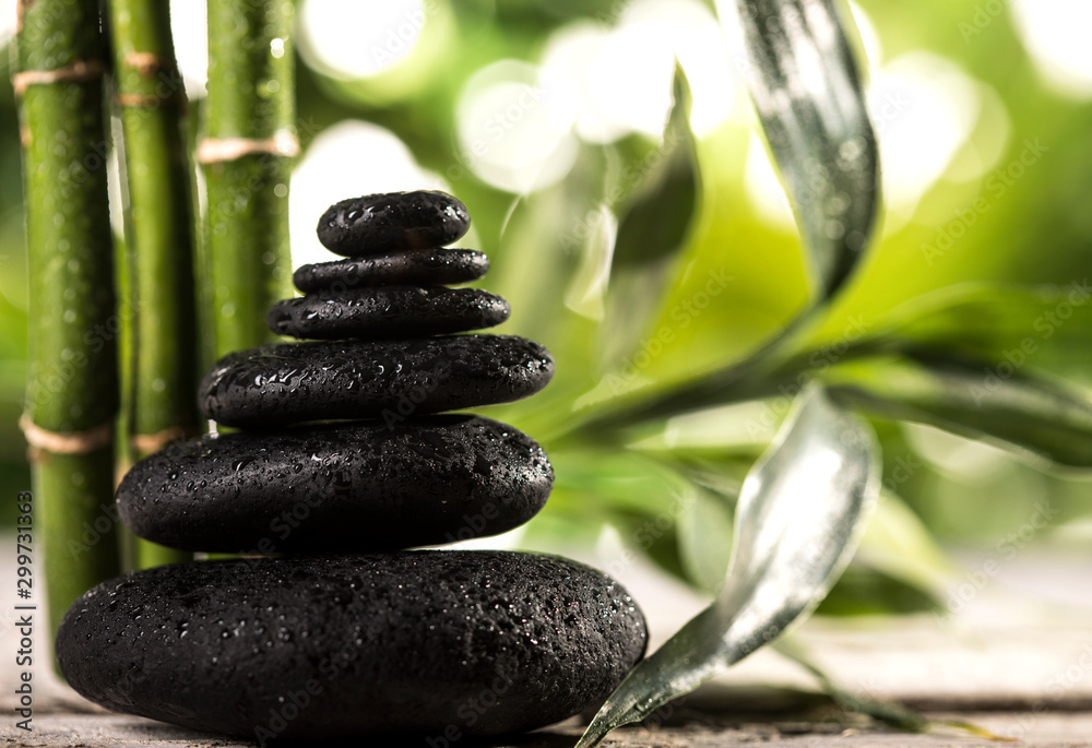 Grean bamboo leaves over zen stones pyramid on tropical leaves background Grean bamboo leaves over zen stones pyramid on tropical leaves background