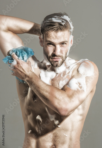 Spa, hygiene, relax. Naked man taking shower with foam. Man in shower. Fitness man with muscular body taking shower in morning. Handsome muscular man in shower. Sexy guy wash with sponge in bathroom.