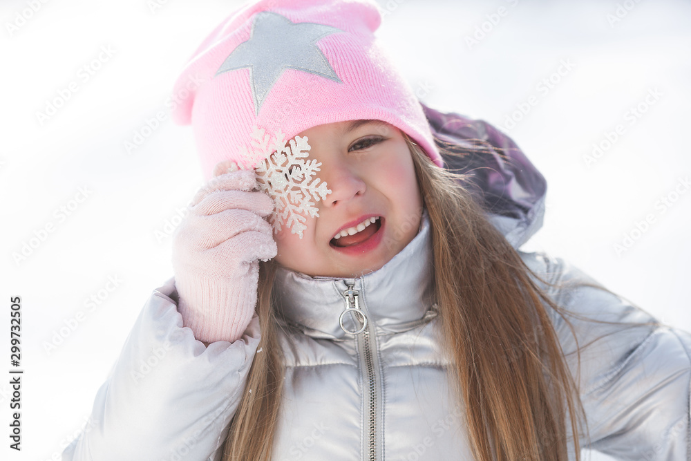 Pretty little girl holding snowflake outdoors. Cute girl on winter background.