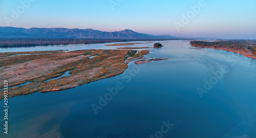 Aerial, east view of Zambezi river during sunset. View on african wilderness, mountains and huge river Zambezi from above. Border river. UNESCO Heritage Site, Mana Pools National Park, Zimbabwe. photo
