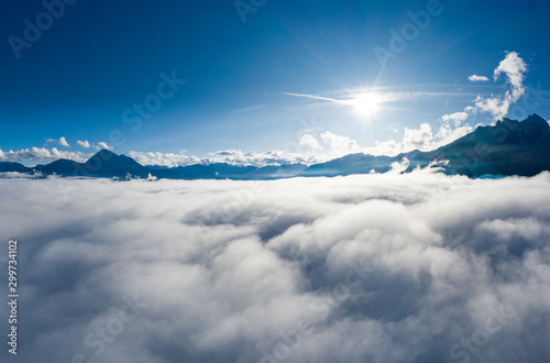 aerial view over cloud bank to tirol mountain alps with sun beams