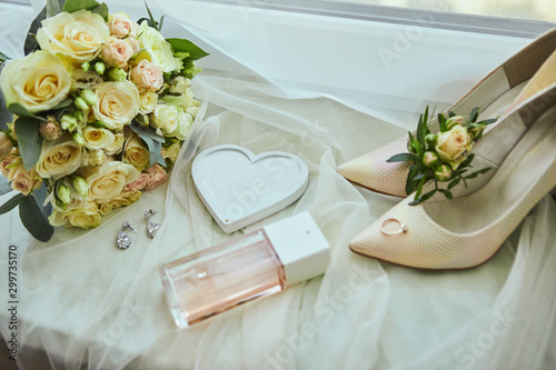 bridal accessories such as shoes, bouquet , ring and perfume lie on a table