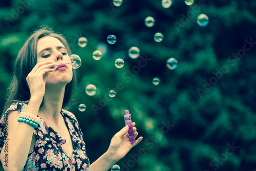 Woman blowing soap bubbles, having fun