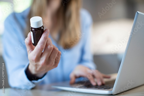Close Up Of Woman At Home Looking Up Information About Medication Online Using Laptop photo