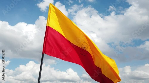 Close up of the official flag of the South Indian state of Karnataka flying against the sky and clouds in the background photo