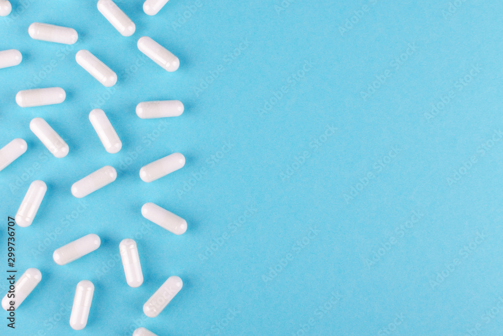 white medicine capsules on blue background with copy space white medicine capsules on blue background with copy space