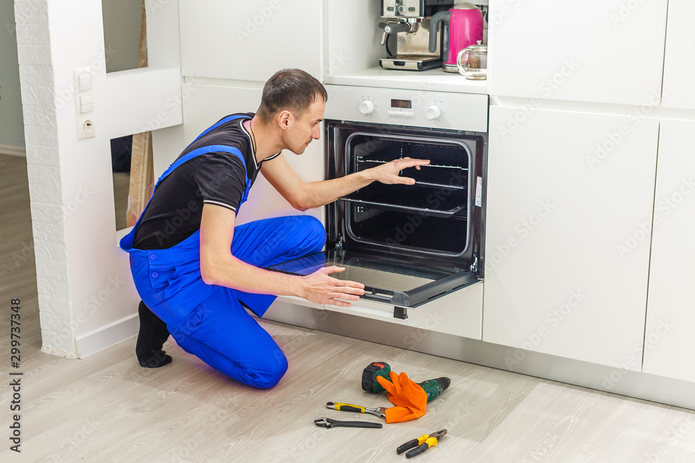 Fotografie Male Technician Sitting Near oven In Kitchen