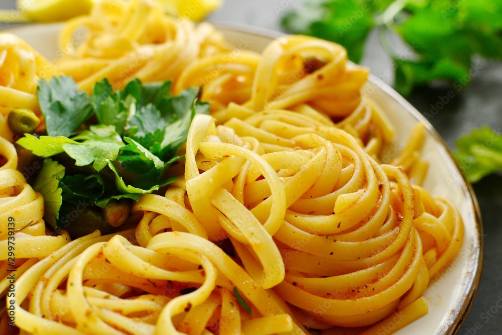 Pasta in a beautiful white plate. Pasta on a light wooden background. Spaghetti with parsley leaves. Macaroni, parsley, lemon, sweet yellow pepper. Pasta in a beautiful white plate. Pasta on a light wooden background. Spaghetti with parsley leaves. Macaroni, parsley, lemon, sweet yellow pepper.