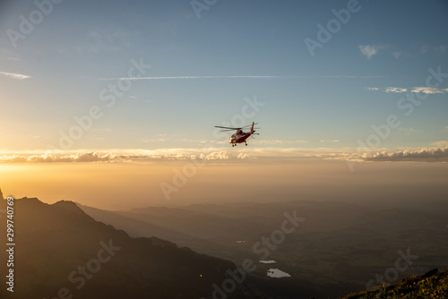 Helikopter fliegt über Berge in den Sonnenuntergang 