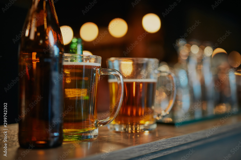 Picture of refreshing beers in bottles and pints on bar counter. Pub interior. - obrazy, fototapety, plakaty 