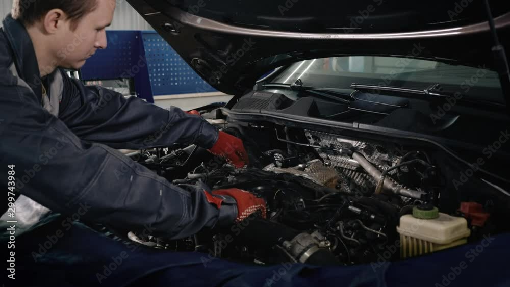 Car service, repair, maintenance and people concept - mechanic man working at workshop. Proffesional car maintenance at service station. Car service, repair, maintenance and people concept - mechanic man working at workshop. Proffesional car maintenance at service station.