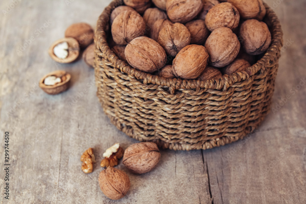 Walnuts in a round wicker basket on a wooden background. Top view. Copy, empty space for text Walnuts in a round wicker basket on a wooden background. Top view. Copy, empty space for text