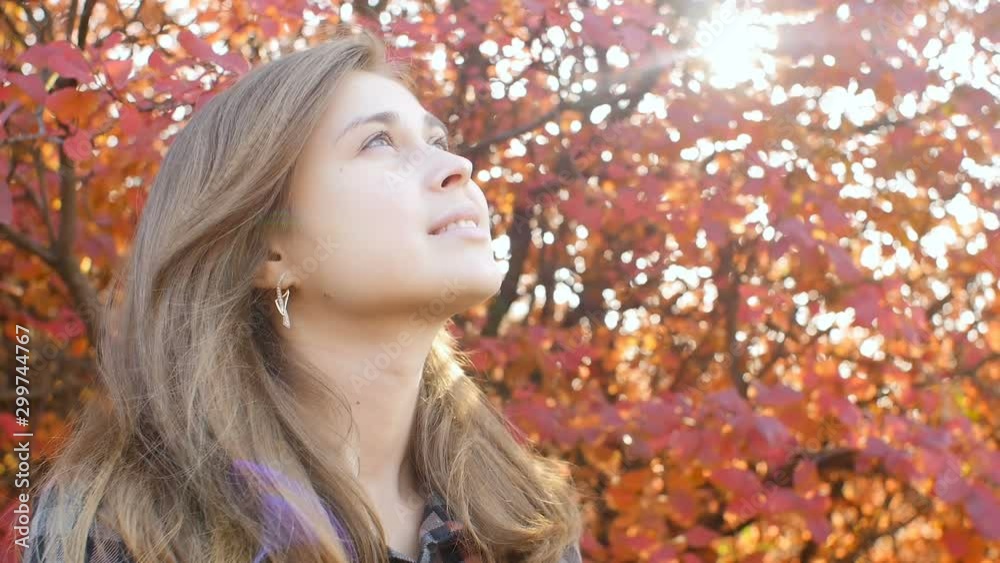 profile of a beautiful young woman looking up gratefully, girl walking through autumn nature in a park