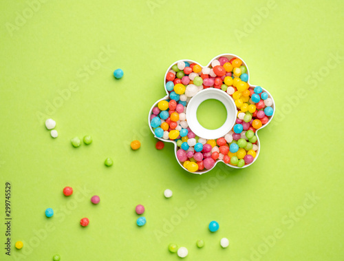 Creative layout of flower shape with colorful candies over green background