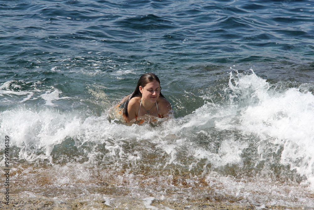 A girl swims in the sea off the coast
