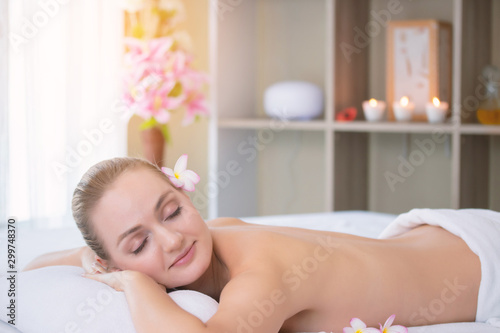 Attractive beautiful girl lying on massage bed in spa salon. Spa aroma therapy and beauty treatments concept.
