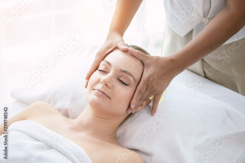 Face massage. Attractive beautiful young woman relax lying on massage bed in spa salon. Spa aroma therapy and massage facial beauty treatment concept.