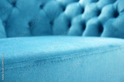 Detail of classical furniture, selective focus. Velour sofa close-up with part of the seat. Turquoise padded fabric upholstery of the sofa. Turquoise velvet with buttons on the upholstered furniture.