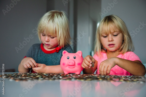 cute girls saving money, kids put coins into piggy bank