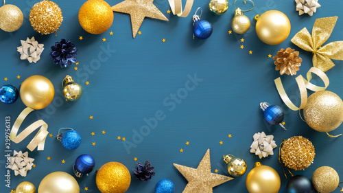 Christmas frame border with golden balls, stars, ribbon on blue background. Flat lay, top view, copy space. Xmas banner mockup, flyer, poster template.