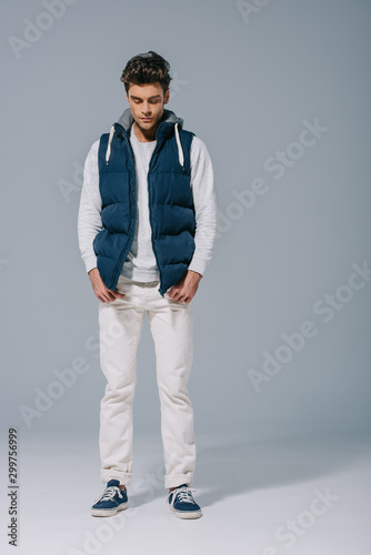 handsome fashionable man posing in waistcoat on grey