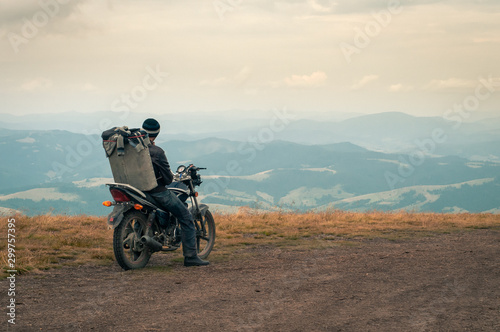 Beautiful mountain landscape. A man, a picker of blueberries, on a motorcycle with a box of berries behind him, is preparing to go down the slope of the Carpathian Mountains.