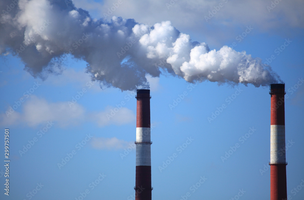 Smoking chimneys on the winter sky background. Heating season. The view of chimney’s tops of the thermal station with puffs of smoke. Thermal electric station, combined heat and power plant