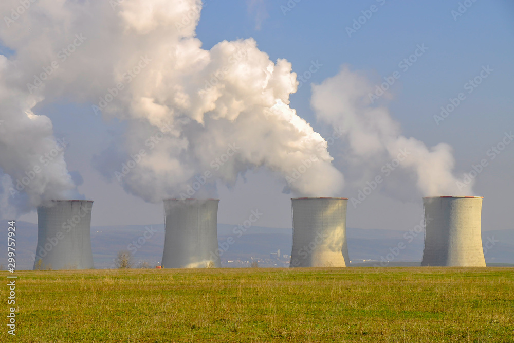 The Tusimice Power Stations. Smoking cooling towers of coal power plant. Heavy industrial coal powered electricity plant with smoke situated in countryside. Ore mountains in background. 