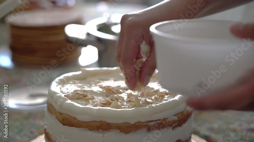 Woman baker puts nuts on a cake with cream. photo