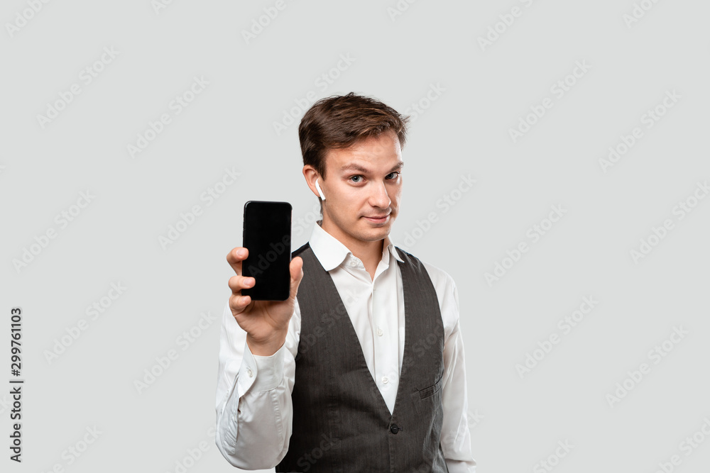 Handsome businessman in a white shirt and grey vest showing screen of a smartphone. Handsome businessman in a white shirt and grey vest showing screen of a smartphone.