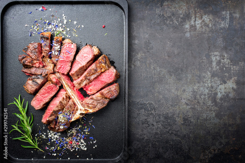 Traditional barbecue dry aged wagyu porterhouse steak sliced with herb and spice as top view on a modern design tray with copy space right