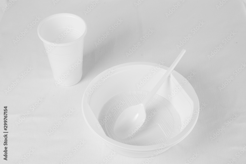 White disposable plastic plate, spoon and glass on a white background. White key. White disposable plastic plate, spoon and glass on a white background. White key.